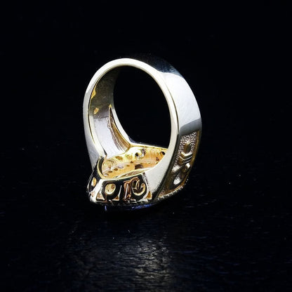 A detail shot of the bishop ring jewelry, revealing the intricate texture of the band and the embossed crosier symbol.